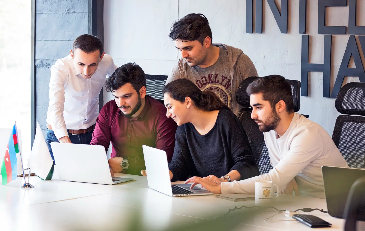 Team of young professionals working together on laptops in modern office.